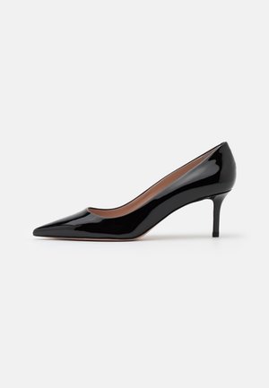 Sort laklæder pumps med spids tå og mellemhøj stiletthæl på hvid baggrund.