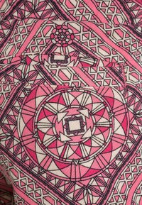 Růžov á tkanina s vzorem obsahujícím geometrické tvary a květinové motivy s černým obrysem. Materiál podobný bavlně s hladkou texturou.