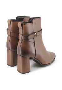 Botas de cuero marrón hasta el tobillo con punta afilada, tacones de bloque y una correa decorativa con un detalle de hebilla dorada. Textura suave.