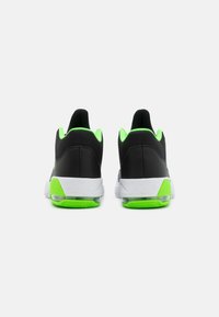 Black athletic shoes with green accents, mesh upper, padded collar, and white sole featuring visible air cushioning and textured tread.
