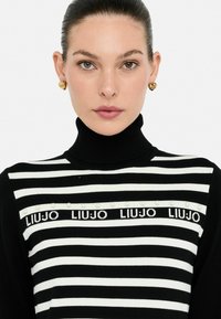 Pullover a collo alto a righe nere e bianche con un'accaduta di perle e dettaglio del logo sul petto, realizzato in un morbido tessuto lavorato a maglia.