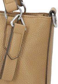 Tan leren handtas met een gestructureerde afwerking, voorzien van zilveren hardware en een ontwerp met dubbele straps. Accentuelementen zijn onder andere gestikte details en metalen ringen.