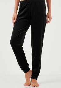 Zwarte fluwelen joggerbroek met een zachte textuur, elastische tailleband en aangesloten enkels. Geschikt voor casual outfits en comfort.