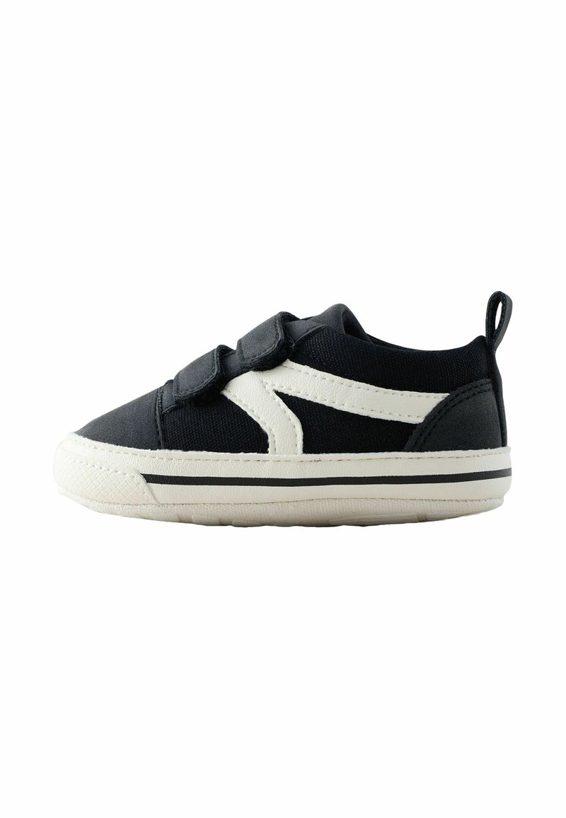Black canvas sneaker with a white rubber sole. Features Velcro straps and a contrasting white side design. Includes a back loop for easy wear.