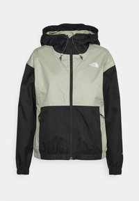 Kurtka typu wiatrówka w jasnym zielonym i czarnym kolorze. Posiada zamek z przodu, regulowany kaptur, elastyczne mankiety oraz boczne kieszenie. Wykonana z lekkiego materiału.