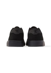 Black suede sneakers with a low silhouette, rubber sole, padded collar, and logo accent on the heel, featuring a smooth, matte finish.