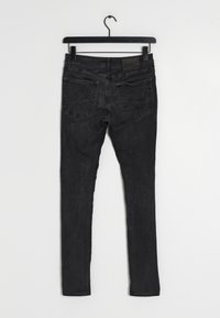 Czarne dżinsy skinny z średnim stanem, pięcioma kieszeniami i subtelnymi detalami w szwie z tyłu. Materiał ma miękką, znoszoną fakturę.