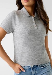 Polo gris à manches courtes en maille avec col, doté de trois boutons décoratifs et d'un ourlet côtelé. Texture douce.