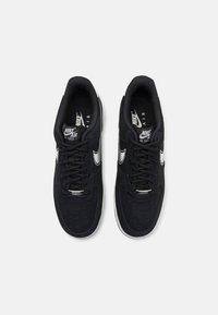 Adidași negri din suede, cu vârf rotund, o dantelă albă Nike și șireturi negre. Ușor capitonați în jurul gleznei și cu detalii perforate pe vârf.
