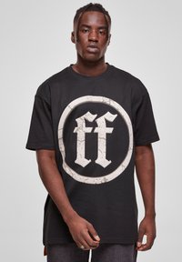 Black oversized t-shirt made of cotton, featuring a large distressed white circular logo with "ff" in the center. Short sleeves, crew neck.