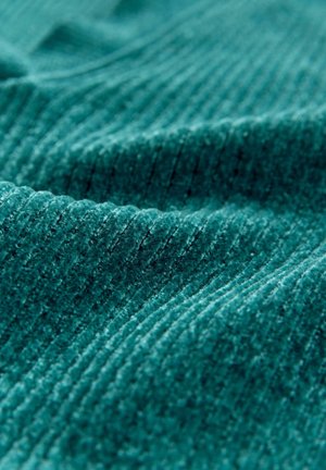 Close-up of soft teal corduroy fabric with distinct vertical ridges and subtle folds.