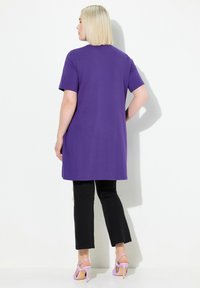 Lila t-shirt med korta ärmar, i en avslappnad passform. Kombinerad med svarta skräddarsydda byxor och ljuslila klacksandaler.
