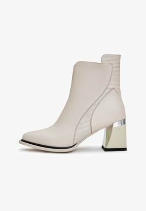 Beige Knöchelstiefel aus glattem Leder, mit gerippten Details und einem geometrischen Blockabsatz mit metallischen Akzenten.