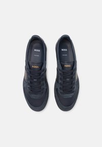 Marina sneakers med en blandning av mocka och släta material, rund tå, platta snören och varumärkesdetaljer i guld på sidan och på tungan.