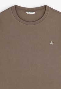 Bruine katoenen T-shirt met een geribbelde ronde halslijn en een klein wit doodskop- en kruisbottenlogo op de linkerborst.