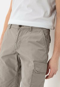 Hellgraue Cargo-Hosen aus leichtem Stoff, ausgestattet mit Seitentaschen, einer Knopfverschluss und einer lässigen Passform für Komfort und Beweglichkeit.
