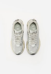 Lichtgrijze sport schoenen gemaakt van mesh en synthetische materialen. Voorzien van een gevoerde zool, ronde neus en vetersluiting.