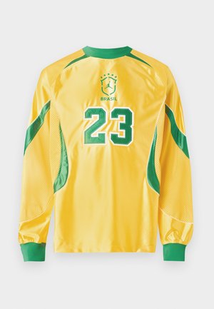 Κίτρινη αθλητική φανέλα με μακριά μανίκια και πράσινες λεπτομέρειες, αριθμός 23 στην πλάτη και το έμβλημα της Βραζιλίας με αστέρια από πάνω.