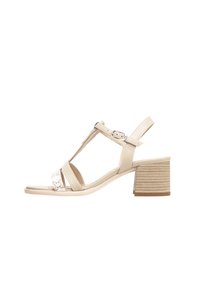 Beige heeled sandals with a T-strap design, featuring a textured block heel and a patterned strap. Smooth leather and adjustable buckle closure.