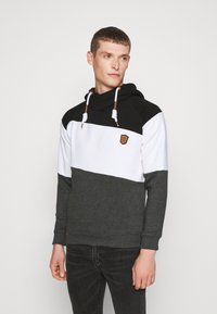 Hoodie met zwarte, witte en donkergrijze kleurblokken. Voorzien van een gestructureerde stof, verstelbare trekkoorden en een badge op de borst.