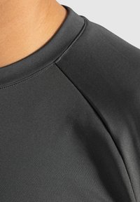 Zwart atletisch shirt met een ronde halslijn, een gladde textuur en raglanmouwen, met een aansluitend ontwerp dat geschikt is voor actieve kleding.