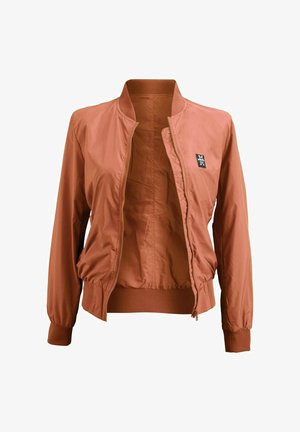 Rust-colored lightweight bomber jacket with ribbed cuffs and hem, front zipper partially open, and small black patch logo on chest.