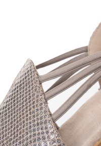 Sandalia beige con tres tiras elásticas y un panel frontal de malla brillante con patrón de diamantes para un ajuste seguro.