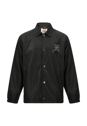 Black, shiny, lightweight jacket with a collared neck, front snap buttons, and elastic cuffs. Features a graphic logo on the chest.