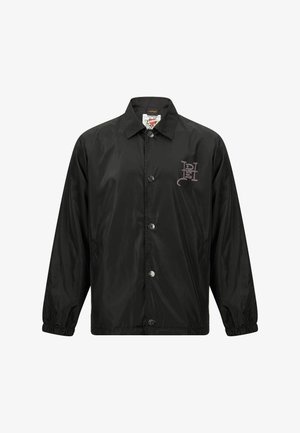 Black, shiny, lightweight jacket with a collared neck, front snap buttons, and elastic cuffs. Features a graphic logo on the chest.