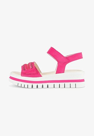 Pink suede sandals with a chunky white platform sole and pink accent. Features an ankle strap and woven detail on the upper.