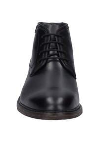 Botas de tobillo de cuero negro con punta redondeada, suela plana y cordones tradicionales con seis ojetes y un ligero detalle de costura.