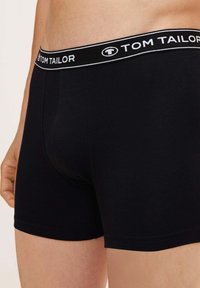 Črne bombažne bokserice s prilagojeno zasnovo in elastičnim pasom, na katerem je bel logotip "TOM TAILOR" na črni podlagi.