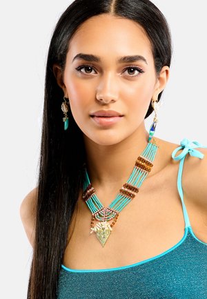 Collier de perles turquoise avec accents dorés et design complexe ; accompagné de boucles d'oreilles pendantes mêlant couleurs et textures.