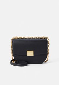 Black leather crossbody bag with a gold chain strap and square clasp. Features a smooth texture and rounded shape.