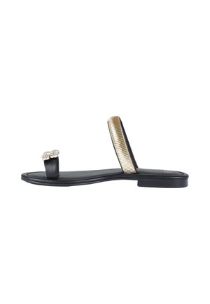 Sandalo nero piatto con passante per l’alluce decorato con gemme trasparenti e cinturino dorato metallizzato e texturizzato sulla parte centrale del piede.