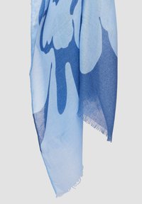 Écharpe légère bleue en tissu doux, présentant un design dégradé allant du bleu clair au bleu foncé et avec des bords frangés pour ajouter de la texture.