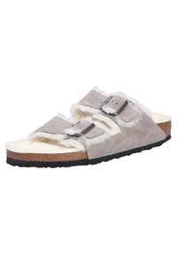 Sandalo in suede grigio con due cinturini regolabili, fodera in pelliccia e soletta in sughero. Suola in gomma nera texturizzata per una buona aderenza.
