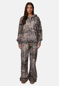 Camo hoodie en broek set met een bruin en grijs bos patroon. Zacht stof met een relaxte pasvorm en elastische tailleband.