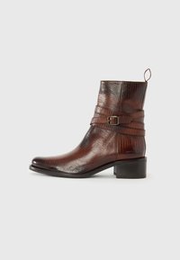 Bottine en cuir marron avec une surface texturée, détails de sangle à boucle et un petit talon carré. Caractéristiques : bout rond et tirette.