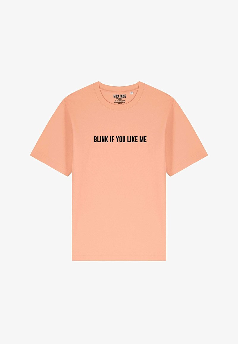 T-shirt di cotone color pesco con maniche corte e collo rotondo. La parte frontale presenta un testo nero in grassetto: "FALLO SE TI PIACCIO."