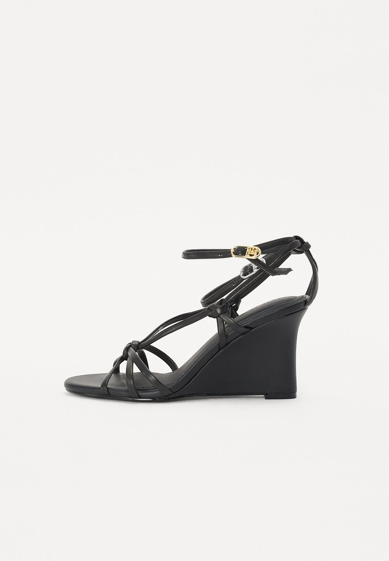 Sandales en wedge noires avec de fines lanières croisées et une sangle de cheville réglable avec une boucle dorée. Finition en cuir lisse.