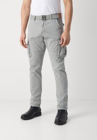 Light gray cargo pants with multiple side pockets, durable fabric, straight fit, and a belted waist. Worn with black ankle boots.