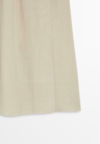Beige stoffen rok met zichtbare naaddetail die verticaal loopt nabij het midden.