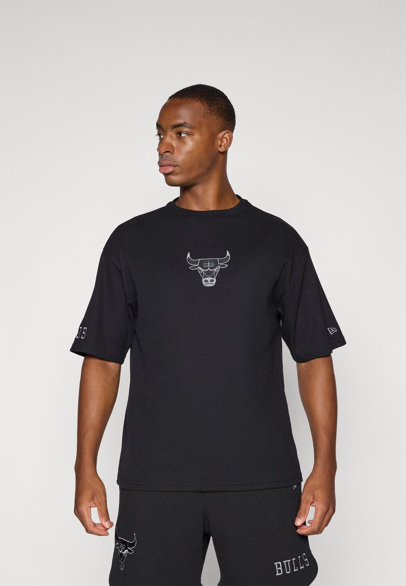 Black short-sleeve t-shirt made of ribbed fabric, featuring a gray embroidered bull logo at the chest. Accompanied by matching shorts.