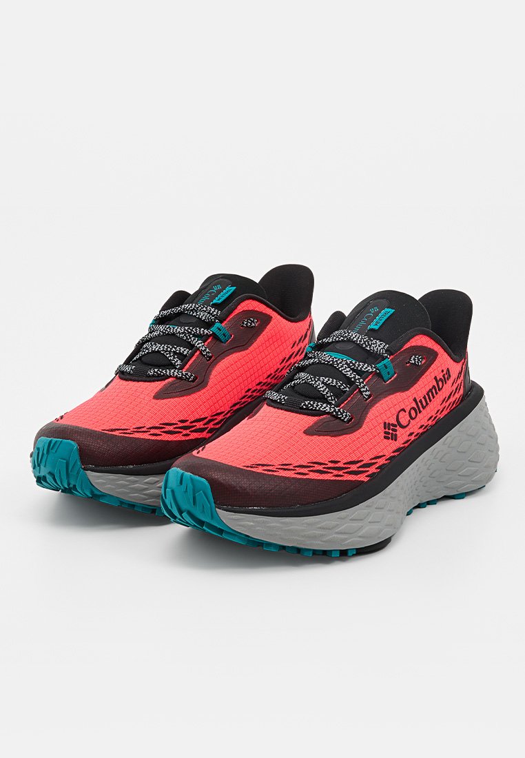 Par de zapatillas de running Columbia rojas con detalles en negro y turquesa, cordones estampados y suelas gruesas grises.