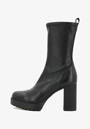 Stivaletto in pelle nera con tacco largo, punta arrotondata e suola testurizzata. Presenta un design elegante e una chiusura con zip sul retro.