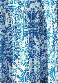 Blau gemusteter Stoff mit komplizierten floralen und geometrischen Designs. Das Material hat eine weiche Textur mit Rüschendetails am Saum.