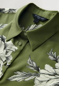 Zelená košeľa s kvetinovým vzorom, s golierom, s čiernobielymi kvetmi, hladkým materiálom a zapínaním na gombíky.
