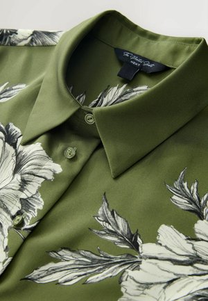 Vihreä kukkakuvioitu paita, jossa on kauluksellinen pääntie. Paidassa on mustavalkoisia kukkakuoseja, sileä pinta ja napit edessä.