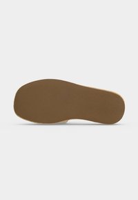 Semelle de chaussure plate en caoutchouc marron avec une texture lisse, montrée vue du dessous sur un fond clair uni.